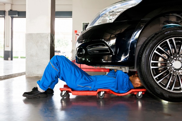 Mechanic,In,Blue,Uniform,Lying,Down,And,Working,Under,Car