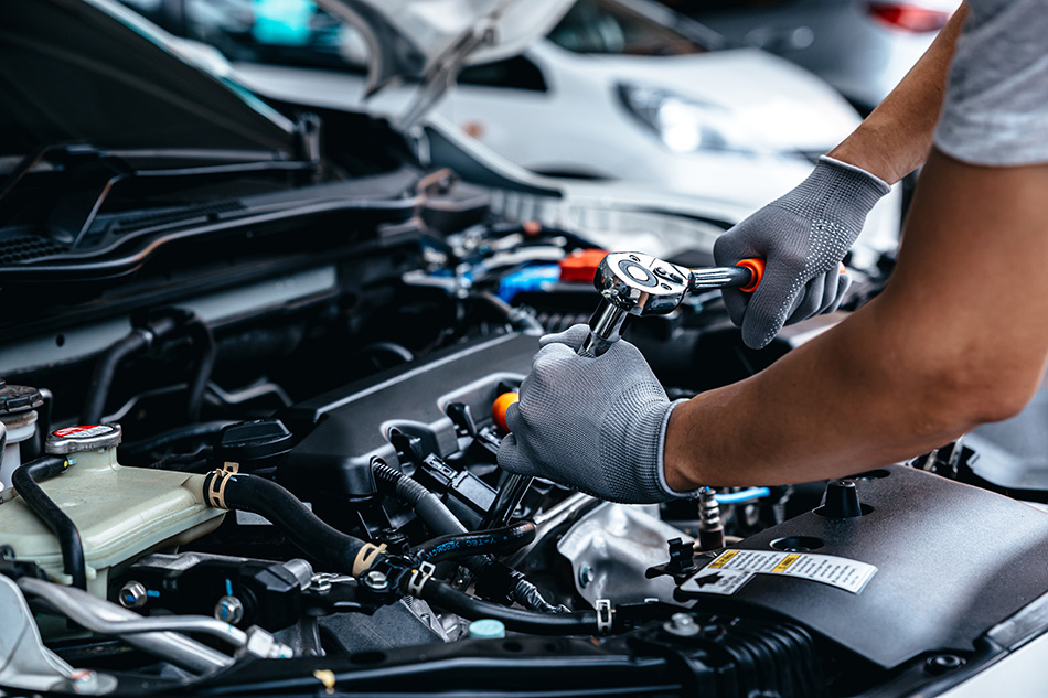 Mechanic using wrench while working on car engine at garage workshop, Car auto services and maintenance check concept.